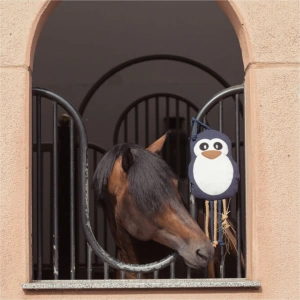 The Eskadron Penguin Stable Toy is hung outside a stable with a bay horse with a black mane whos playing with it